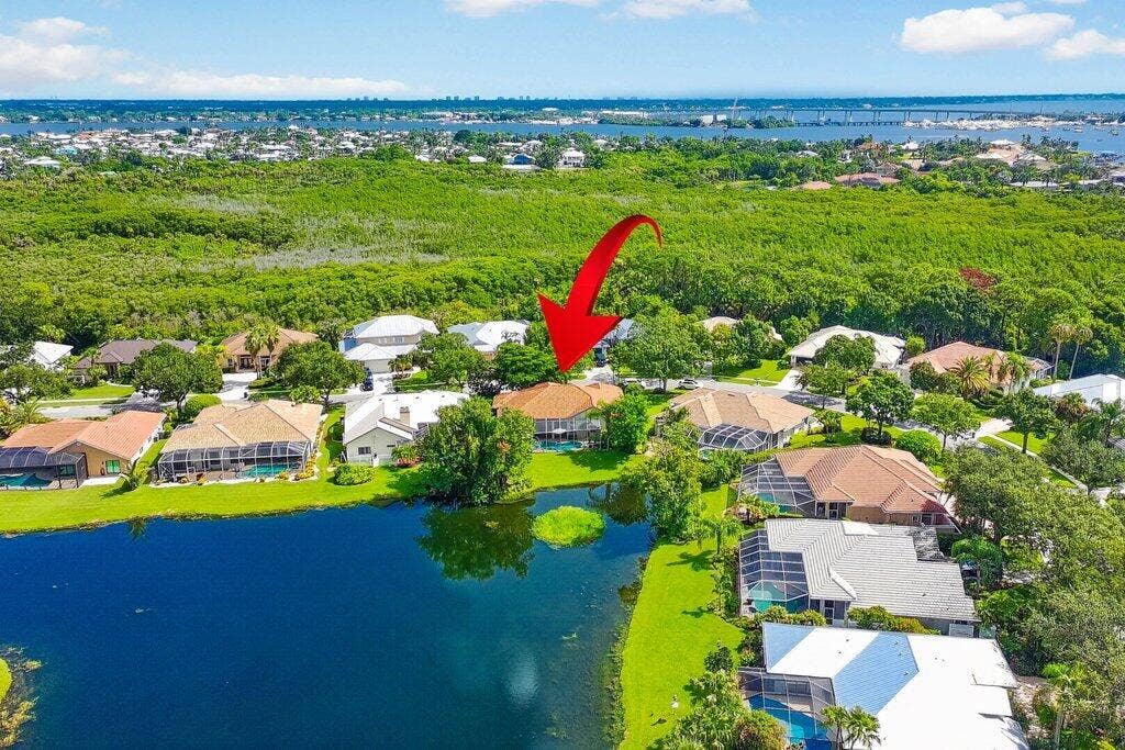 Waterfront property with a screened pool enclosure and lush landscaping