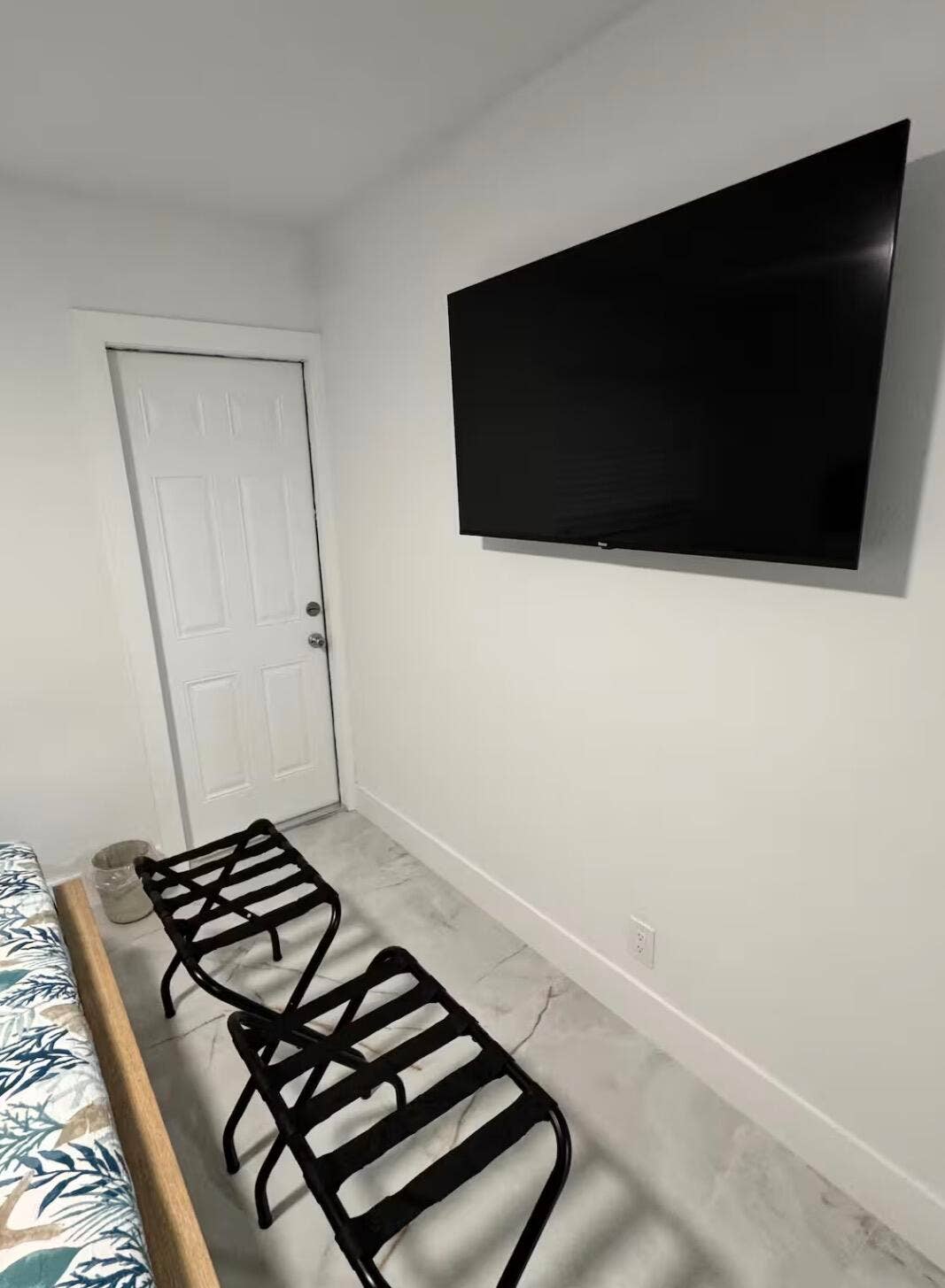 Well-appointed bedroom featuring a wall-mounted TV, comfortable seating area, and elegant marble-look tile flooring