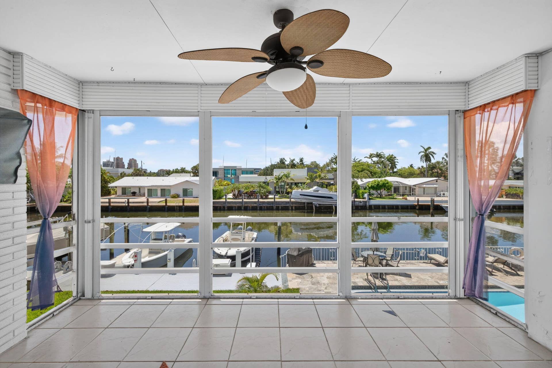 Waterfront property with expansive window framing, tile flooring, and ceiling fan