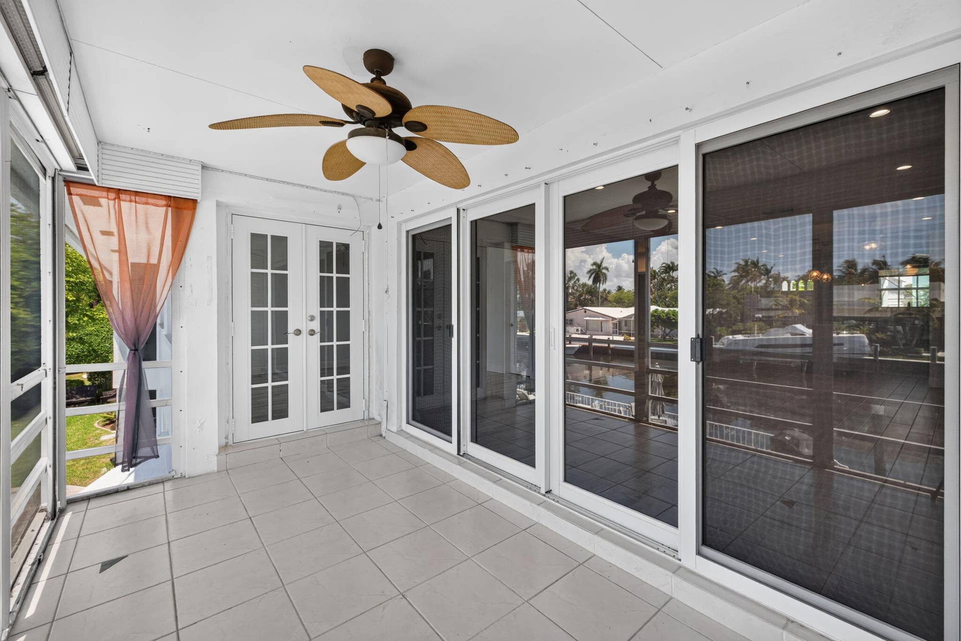 Screened porch featuring a ceiling fan, tiled flooring, French doors, and sliding glass doors