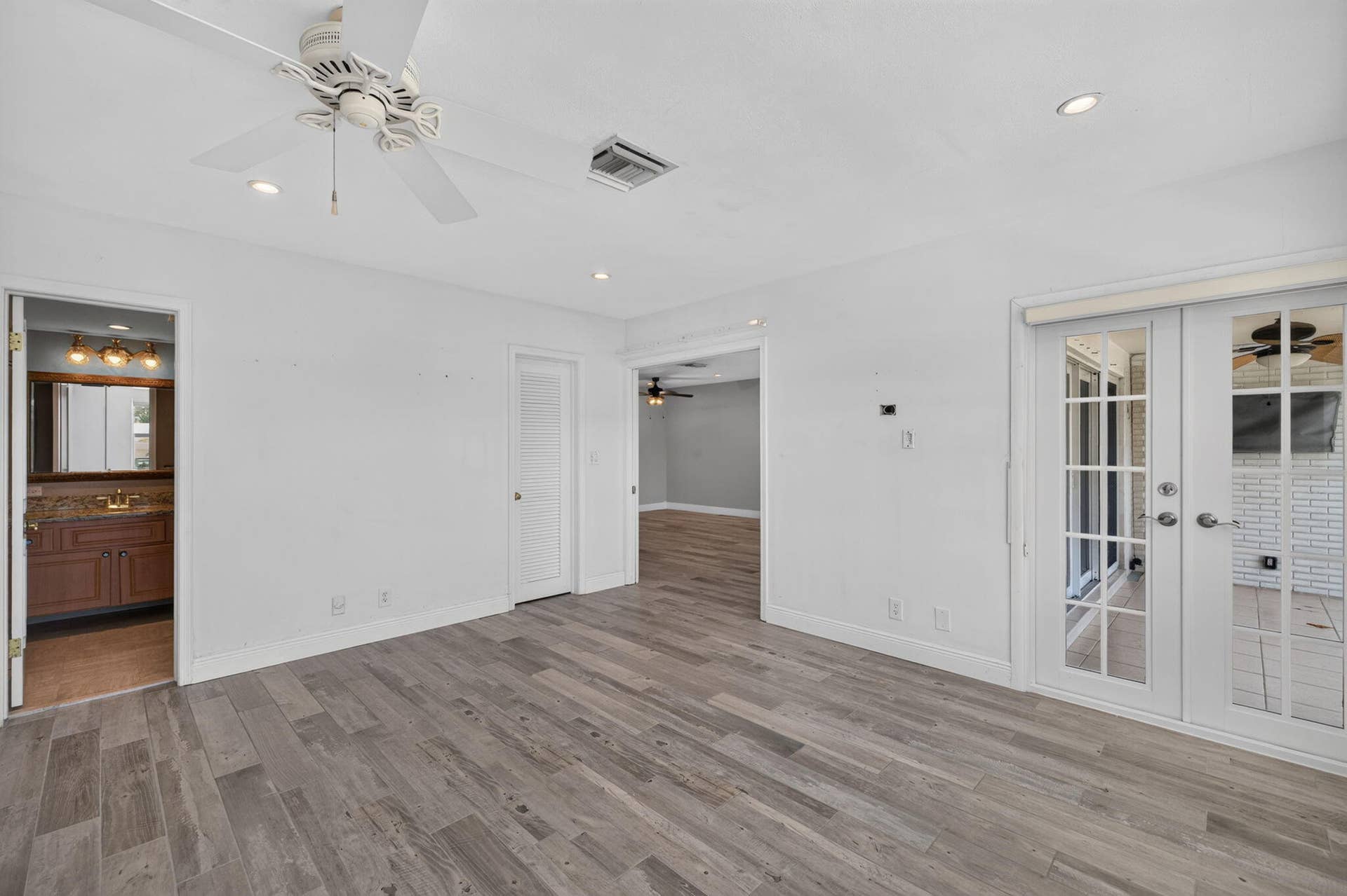 Wood-finish flooring, ceiling fan with light fixture, recessed lighting, and French doors