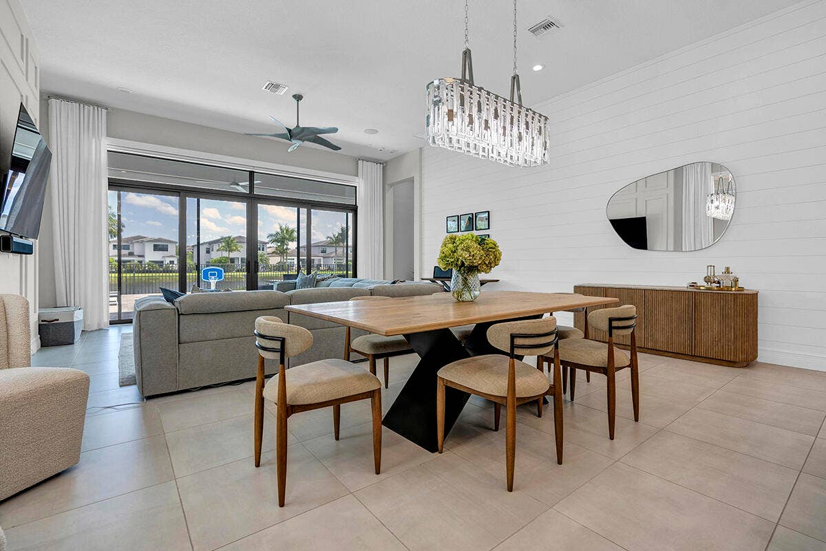 9046 CHAUVET Way, Boca Raton, FL 33496 Open-concept dining and living area featuring large format tile flooring, a linear crystal chandelier, and a shiplap accent wall