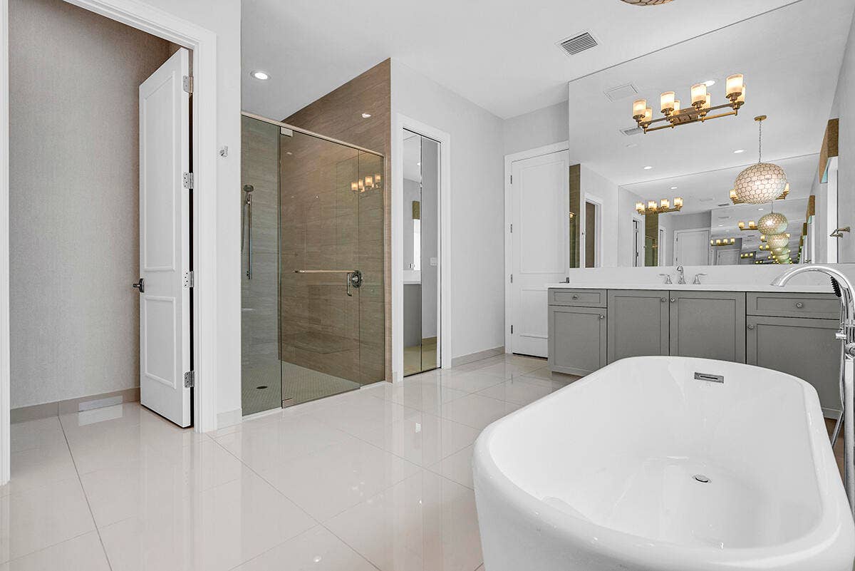 9046 CHAUVET Way, Boca Raton, FL 33496 Freestanding soaking tub with a floor-mounted faucet, complemented by a large vanity with a white countertop and dual undermount sinks