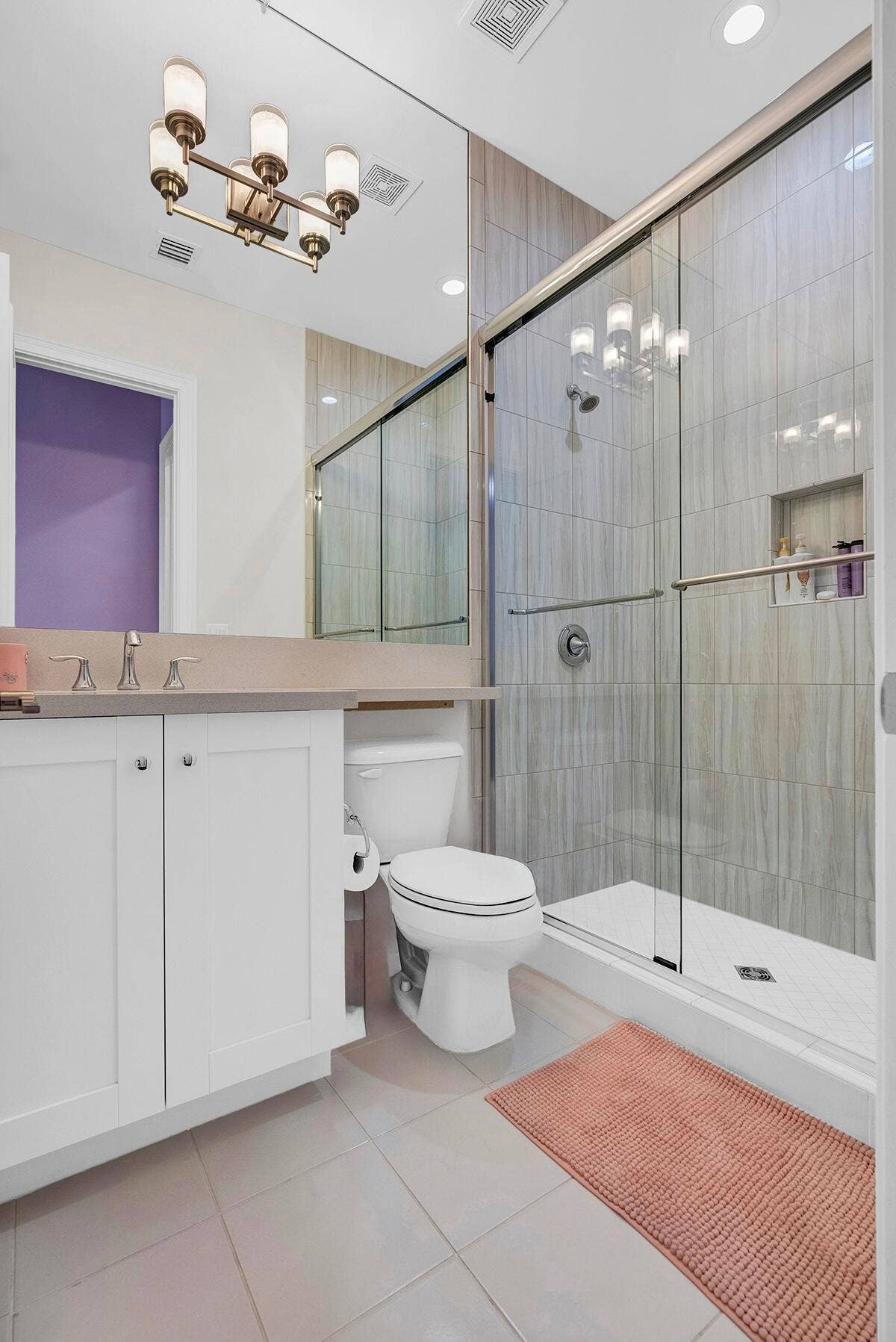 9046 CHAUVET Way, Boca Raton, FL 33496 Bathroom featuring a glass-enclosed shower with vertical tile surround and recessed shelving