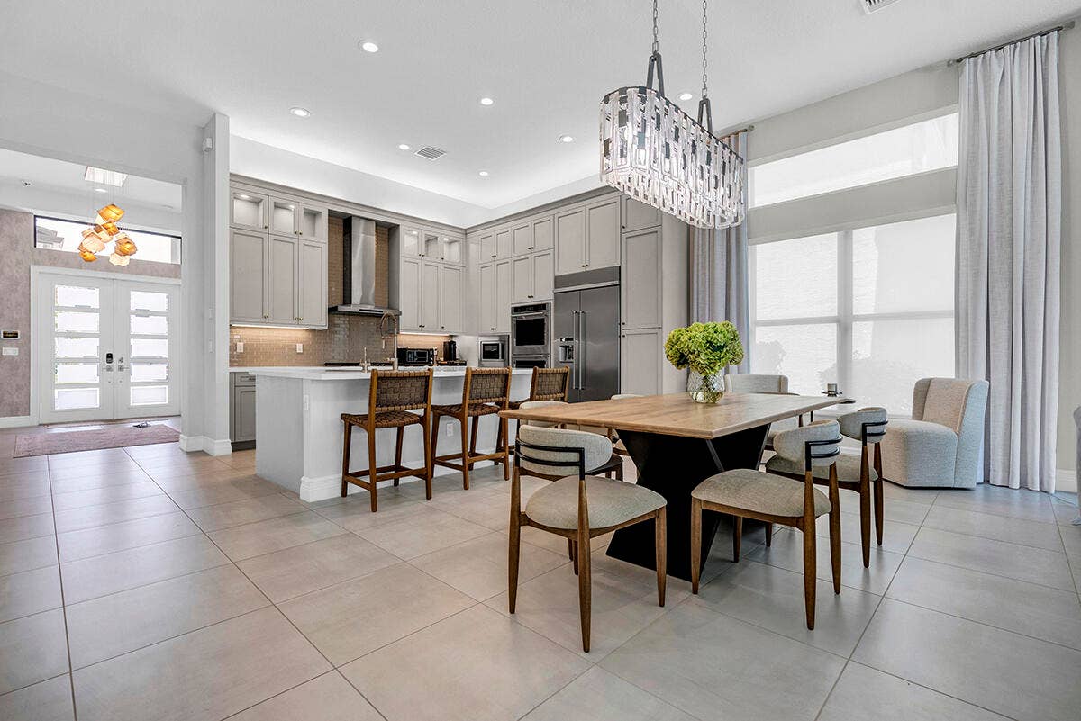 9046 CHAUVET Way, Boca Raton, FL 33496 Spacious open-concept living area featuring large format tile flooring, a gourmet kitchen with extensive cabinetry, a central island with bar seating, and integrated stainless steel appliances