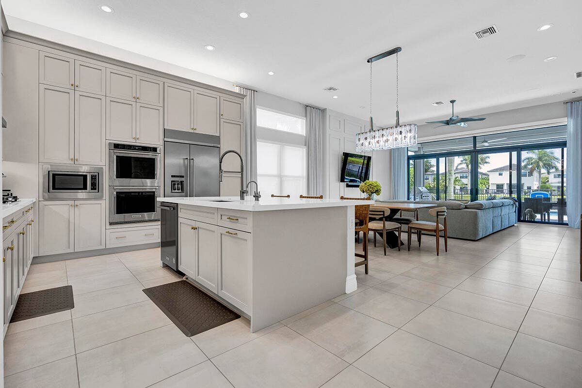 9046 CHAUVET Way, Boca Raton, FL 33496 Contemporary kitchen featuring extensive cabinetry, stainless steel appliances, a center island with sink, and large format tile flooring
