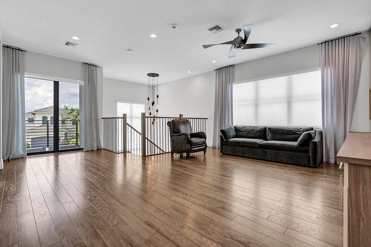 9046 CHAUVET Way, Boca Raton, FL 33496 Spacious room featuring wood-finish flooring, a large sliding glass door with a balcony, and a prominent multi-blade ceiling fan