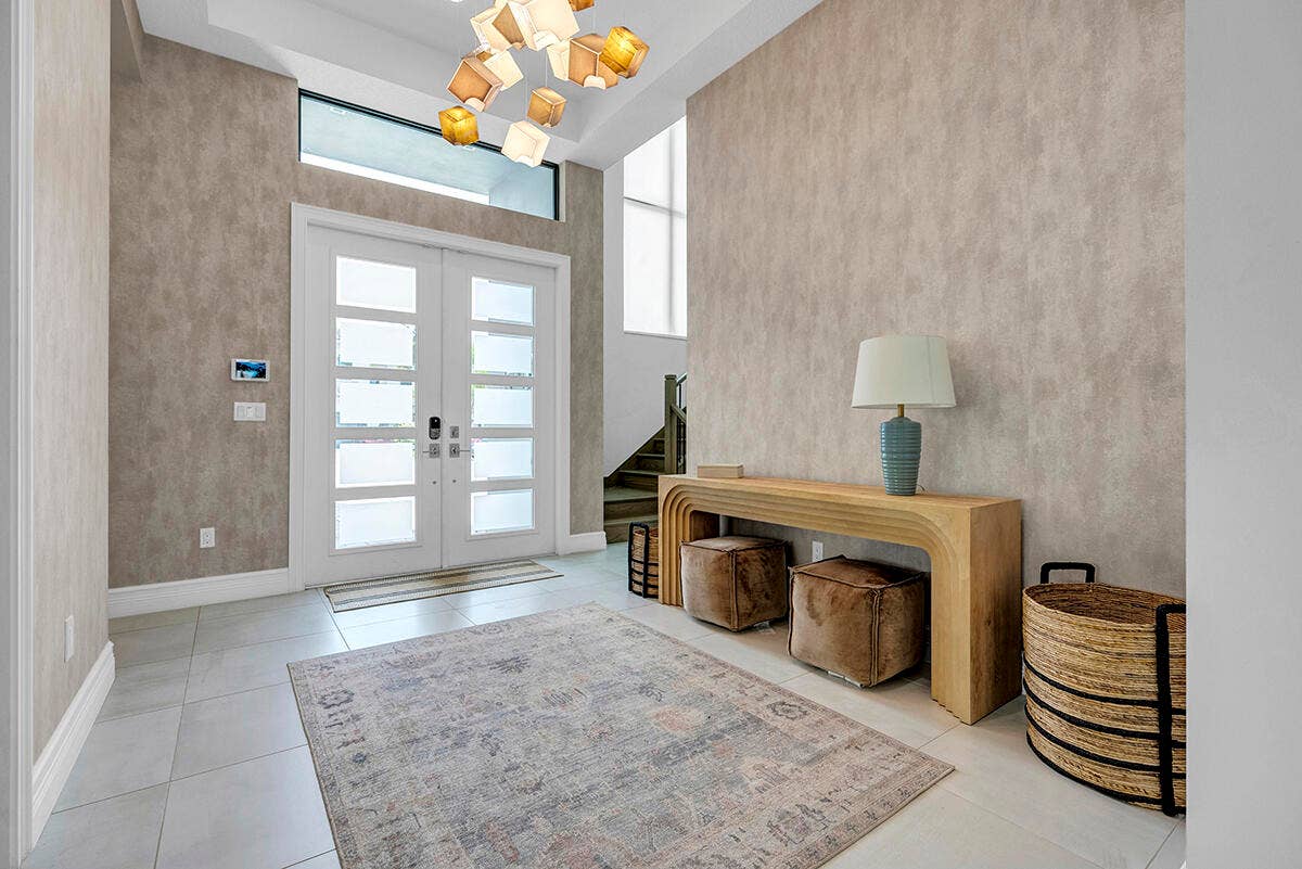 9046 CHAUVET Way, Boca Raton, FL 33496 Grand entry foyer featuring double frosted-pane doors with transom window, light-toned textured wall treatment, and light-colored tile flooring