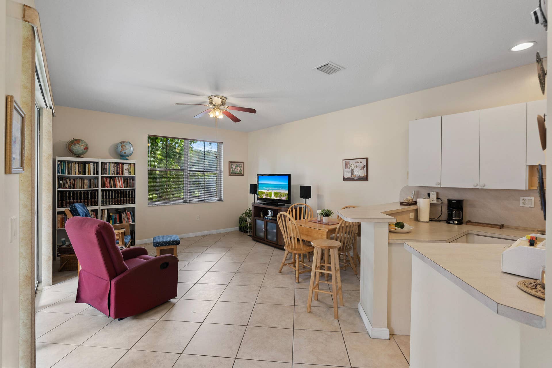 2311 SW 125th Avenue, Miramar, FL 33027 Open concept living area featuring tile flooring, ceiling fan, and a kitchen with white cabinetry and a breakfast bar