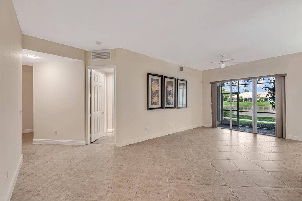 9777 BOWLINE Drive, #102, West Palm Beach, FL 33411 formal living room leading to hallway, primary bedroom, patio