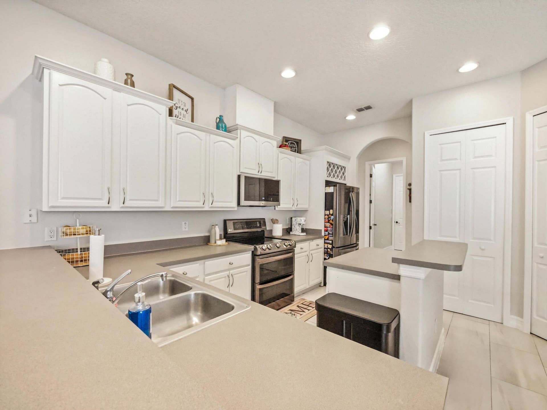 16437 TUDOR GROVE Drive, Orlando, FL 32828 Kitchen featuring white cabinetry, a double basin stainless steel sink, dark countertops, an eat-at peninsula, and recessed lighting