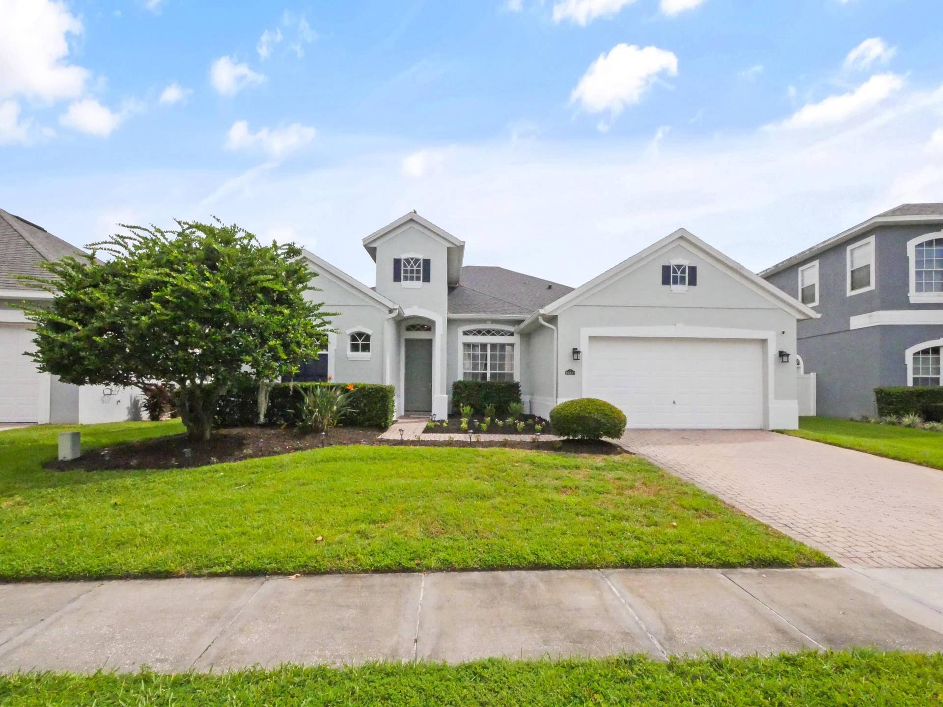 16437 TUDOR GROVE Drive, Orlando, FL 32828 Stucco exterior with a two-car garage, brick paver driveway, and a landscaped front yard