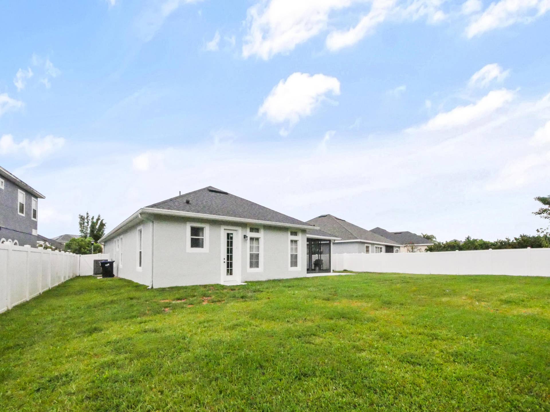 16437 TUDOR GROVE Drive, Orlando, FL 32828 Expansive green lawn, white vinyl fencing, screened patio, and a light-colored exterior