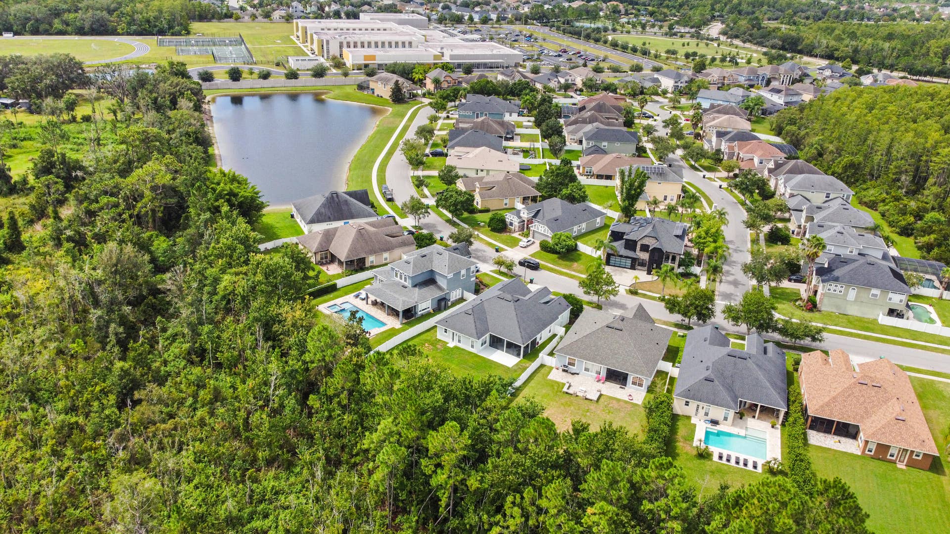 16437 TUDOR GROVE Drive, Orlando, FL 32828 Residential community with a central pond, paved streets, and abundant mature trees