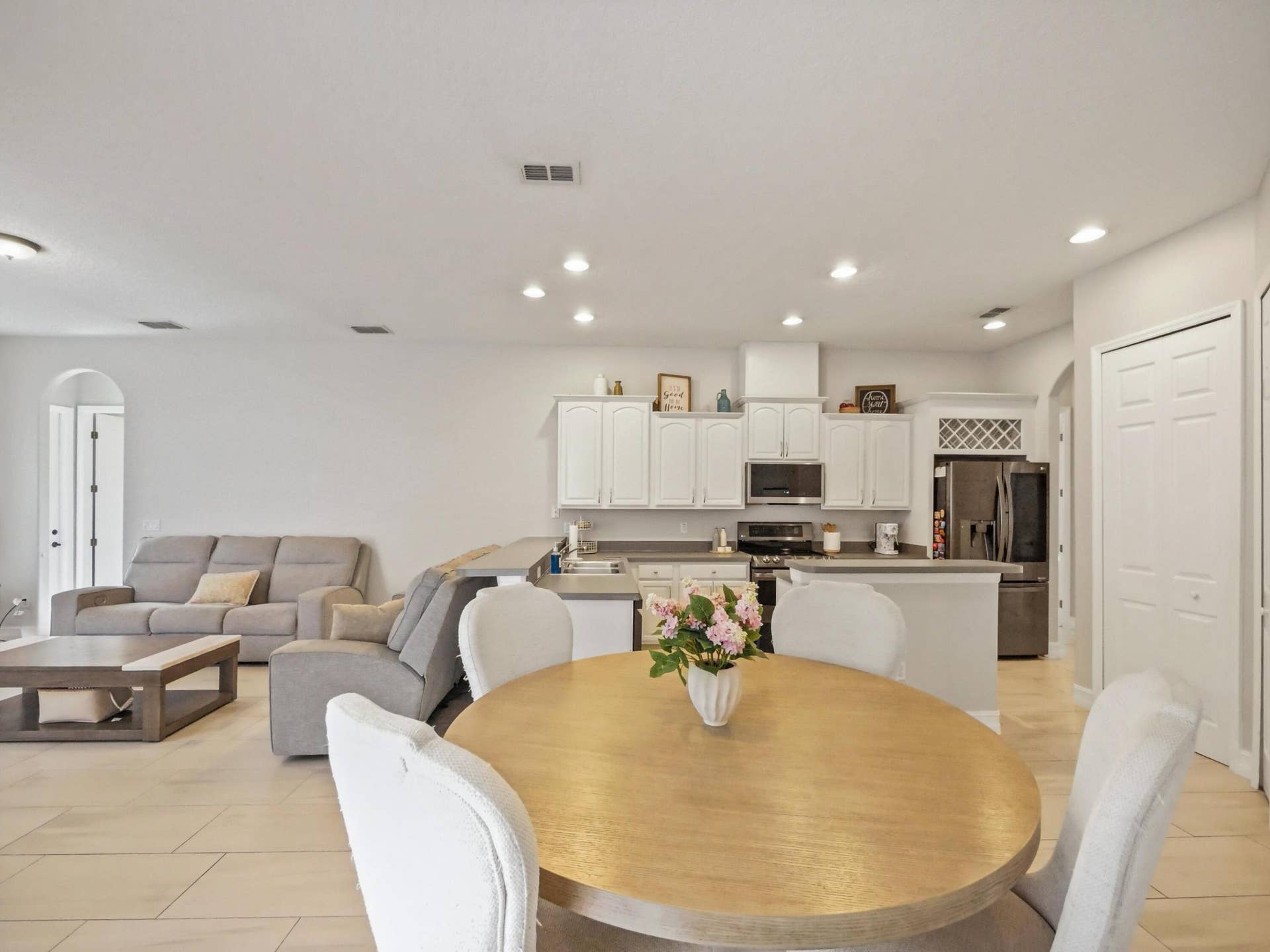 16437 TUDOR GROVE Drive, Orlando, FL 32828 Open-concept living area with light-toned flooring, recessed lighting, and white cabinetry