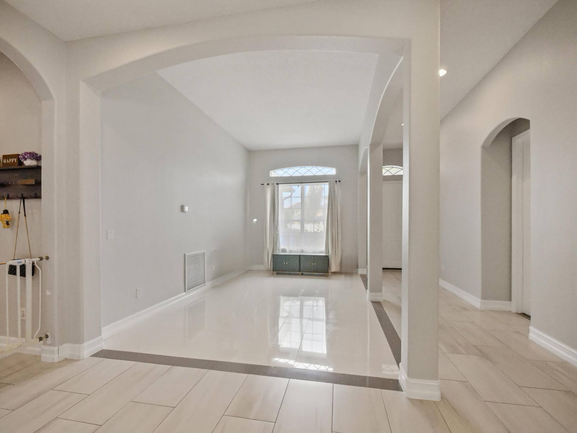 16437 TUDOR GROVE Drive, Orlando, FL 32828 Open living area featuring arched doorways, light-toned tile flooring with a dark accent border, and a front-facing window with decorative mullions