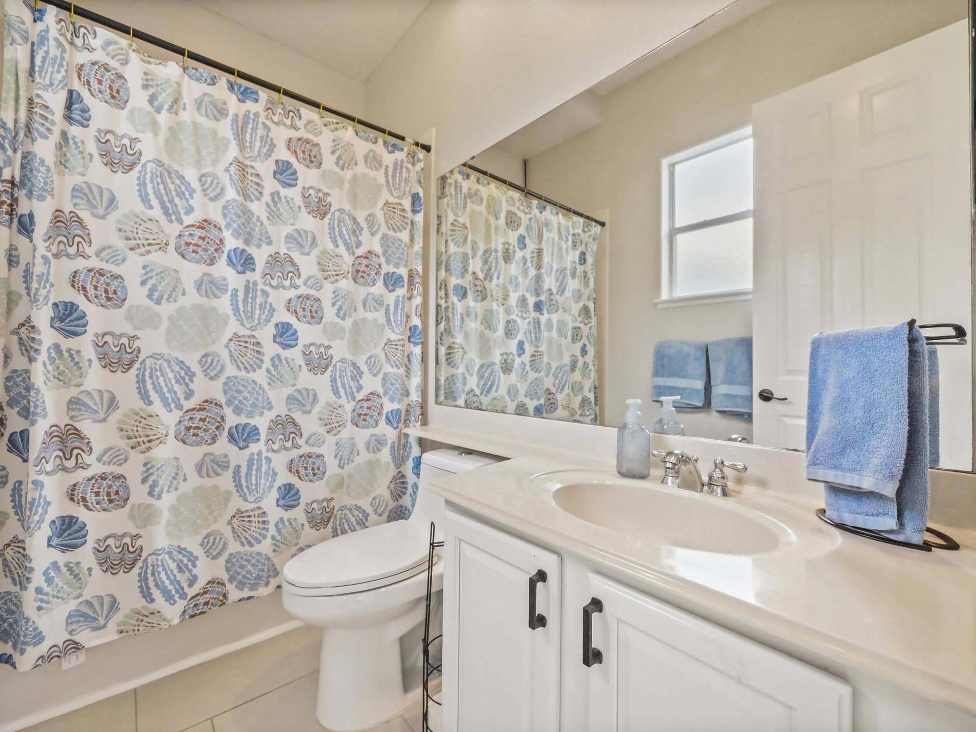 16437 TUDOR GROVE Drive, Orlando, FL 32828 Bathroom featuring a single vanity with an integrated sink, white cabinetry with dark hardware, a framed mirror, and a window