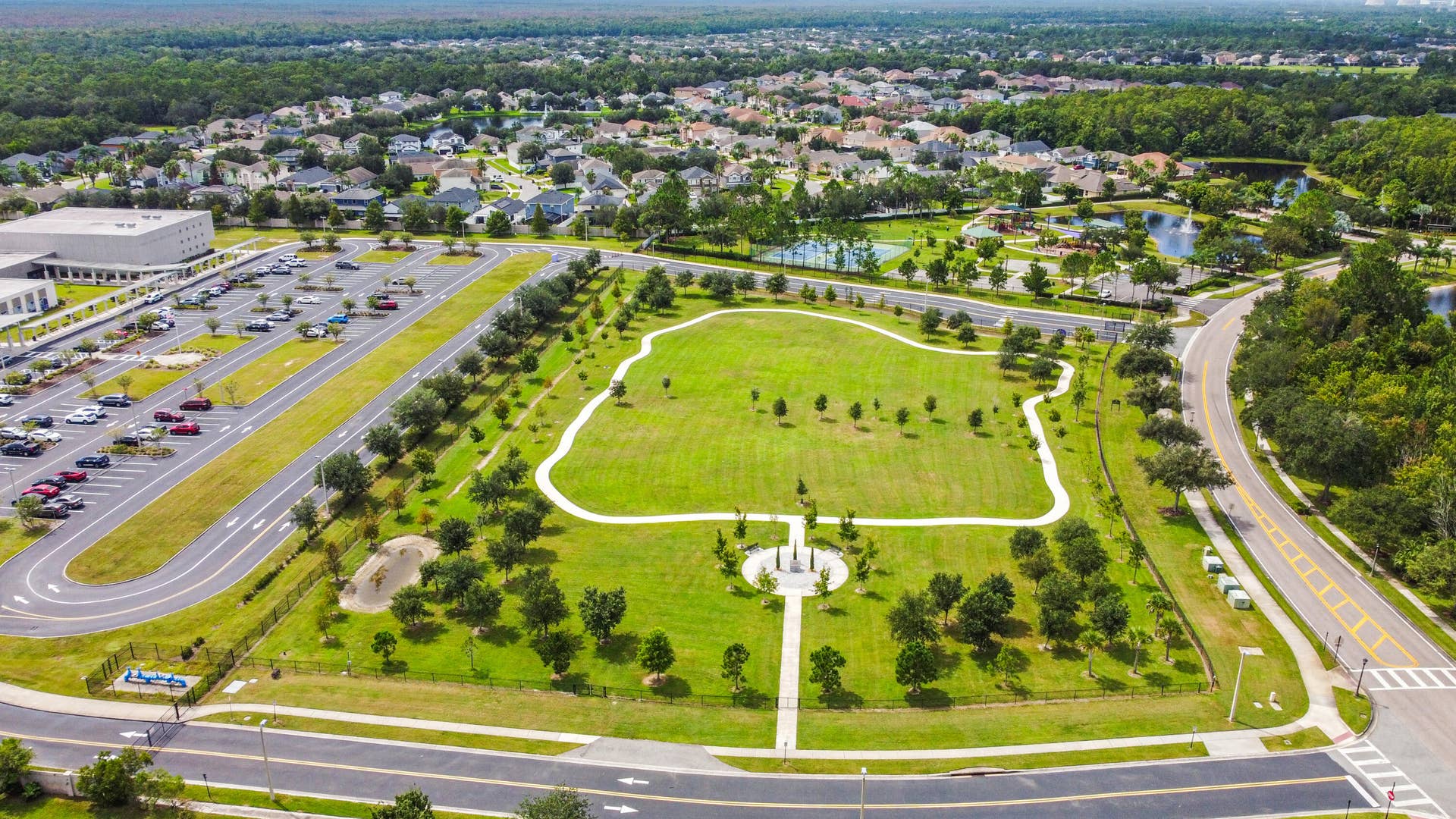 16437 TUDOR GROVE Drive, Orlando, FL 32828 Expansive community green space featuring walking paths, mature trees, and a central monument