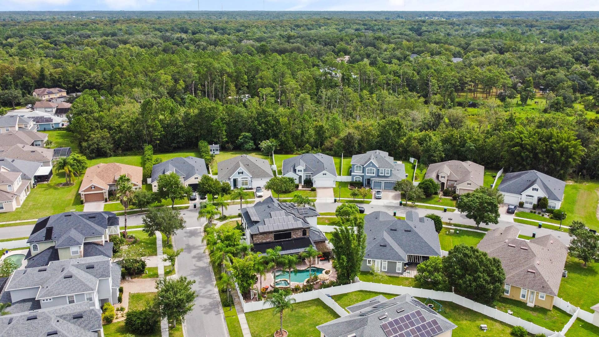 16437 TUDOR GROVE Drive, Orlando, FL 32828 Lush green landscaping bordering residential properties with various architectural styles