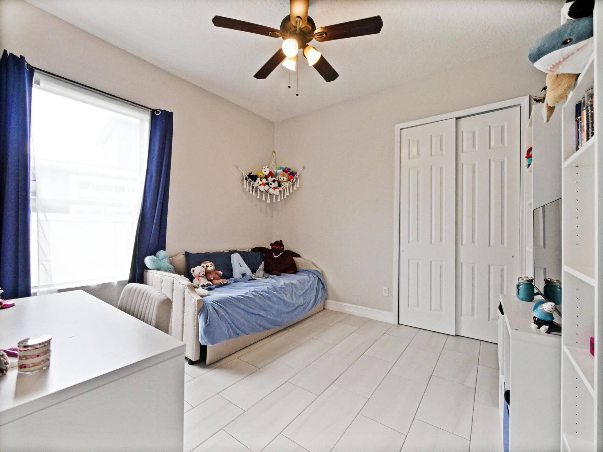 16437 TUDOR GROVE Drive, Orlando, FL 32828 Window with roller shade, wood-finish flooring, ceiling fan with integrated lighting, sliding closet doors, and built-in shelving