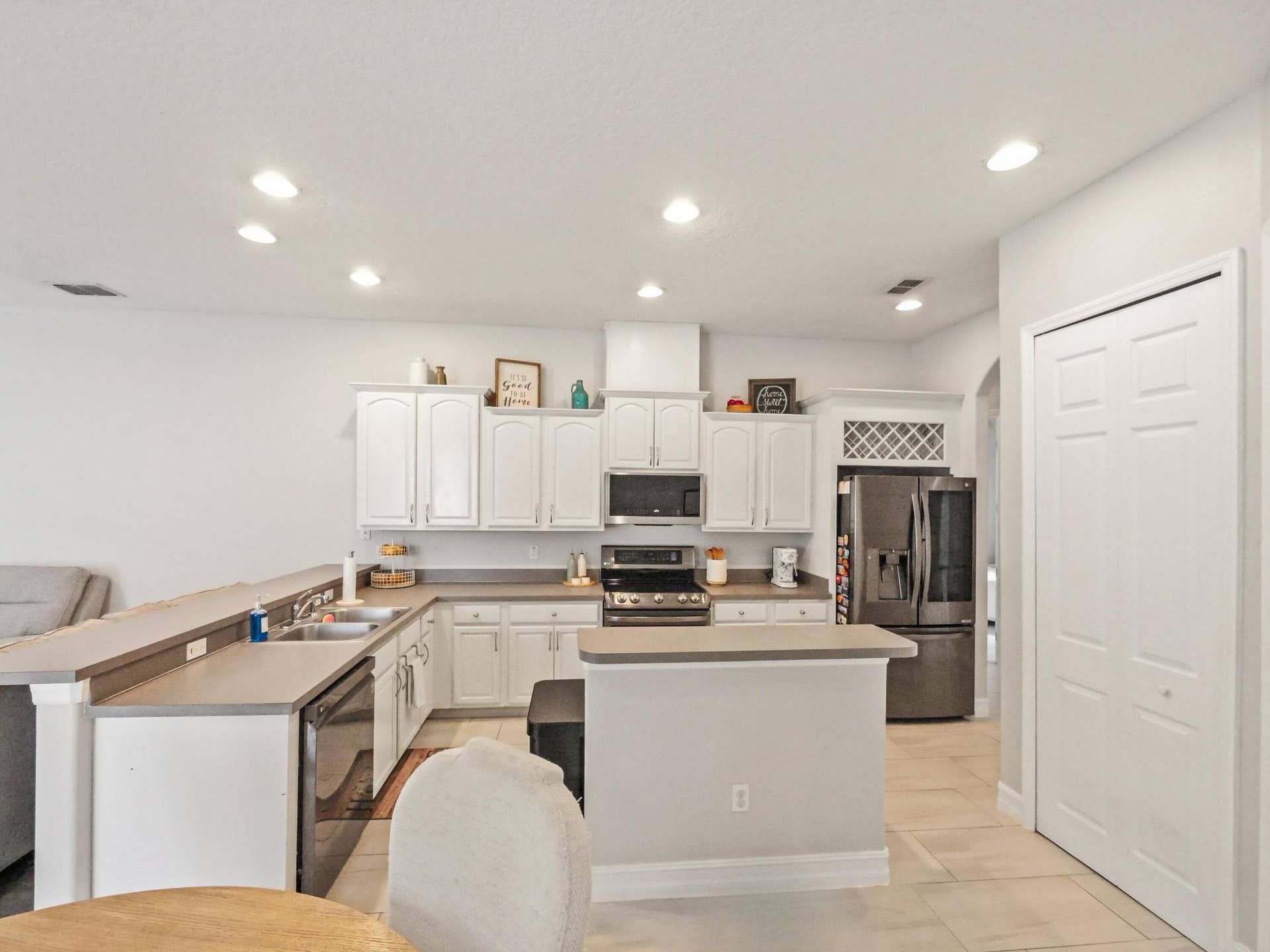 16437 TUDOR GROVE Drive, Orlando, FL 32828 Recessed lighting, white cabinetry, dark tone appliances, kitchen island, and light tile flooring