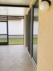 18431 NW 18TH Street, Pembroke Pines, FL 33029 Screened patio with textured flooring, multiple sliding glass doors, and an exterior wall light fixture