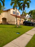 18431 NW 18TH Street, Pembroke Pines, FL 33029 Stucco exterior with a tile roof, mature palm trees, an attached two-car garage, and a concrete sidewalk