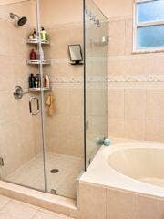 18431 NW 18TH Street, Pembroke Pines, FL 33029 Glass-enclosed shower with a rainfall showerhead, a built-in corner shelving unit, and a tiled shower surround