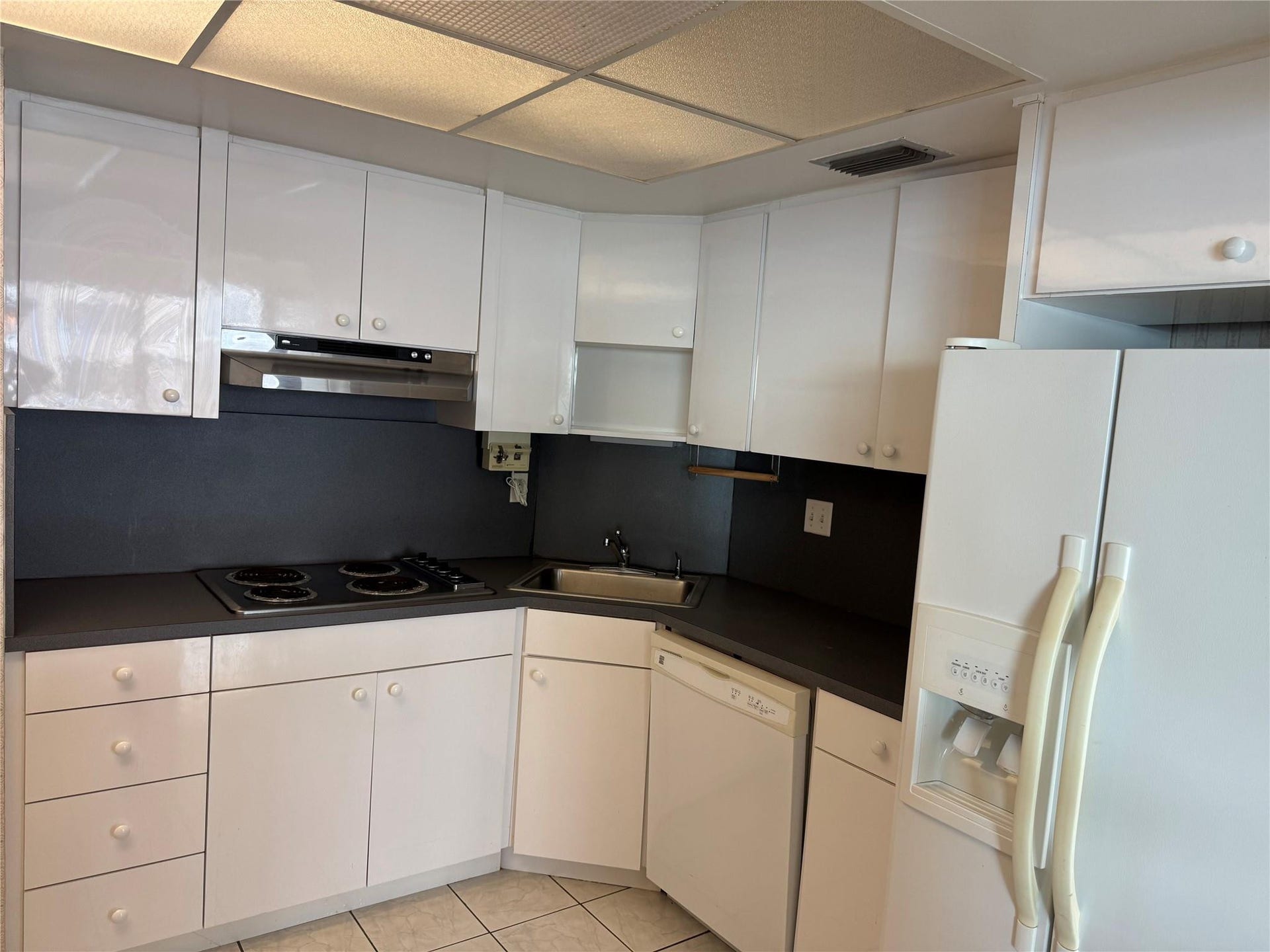 3800 GALT OCEAN Drive, #1508, Fort Lauderdale, Fort Lauderdale, FL 33308 White cabinetry, dark countertops, white refrigerator, built-in cooktop, and stainless steel range hood