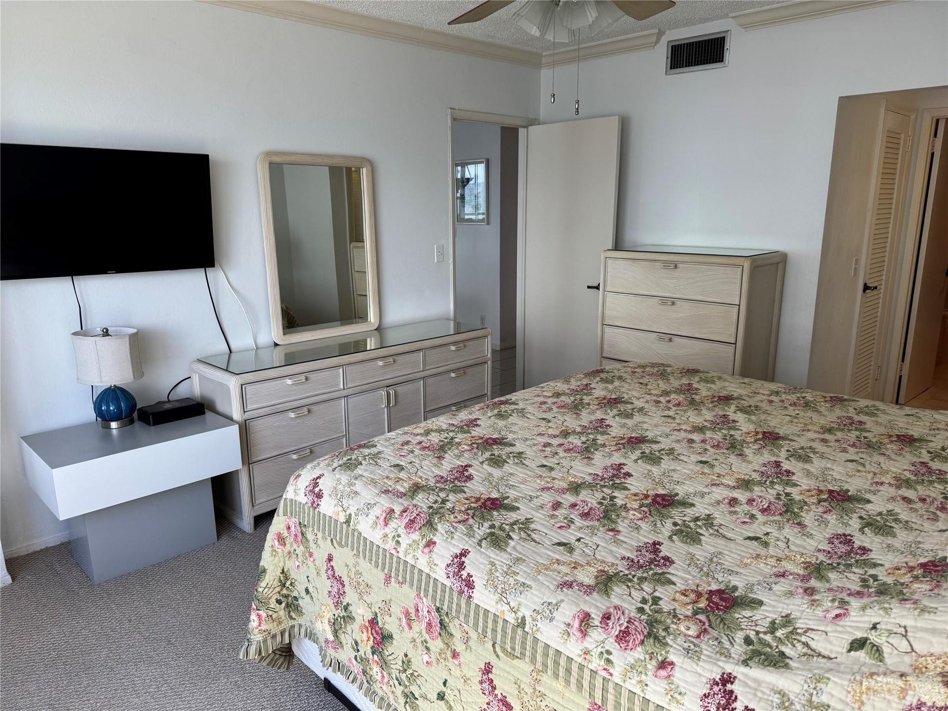 3800 GALT OCEAN Drive, #1508, Fort Lauderdale, Fort Lauderdale, FL 33308 Spacious primary bedroom suite featuring dual mirrored dressers with wood-finish cabinetry, a coordinating wardrobe armoire, wall-mounted flat-screen television, ceiling fan, and carpet flooring throughout