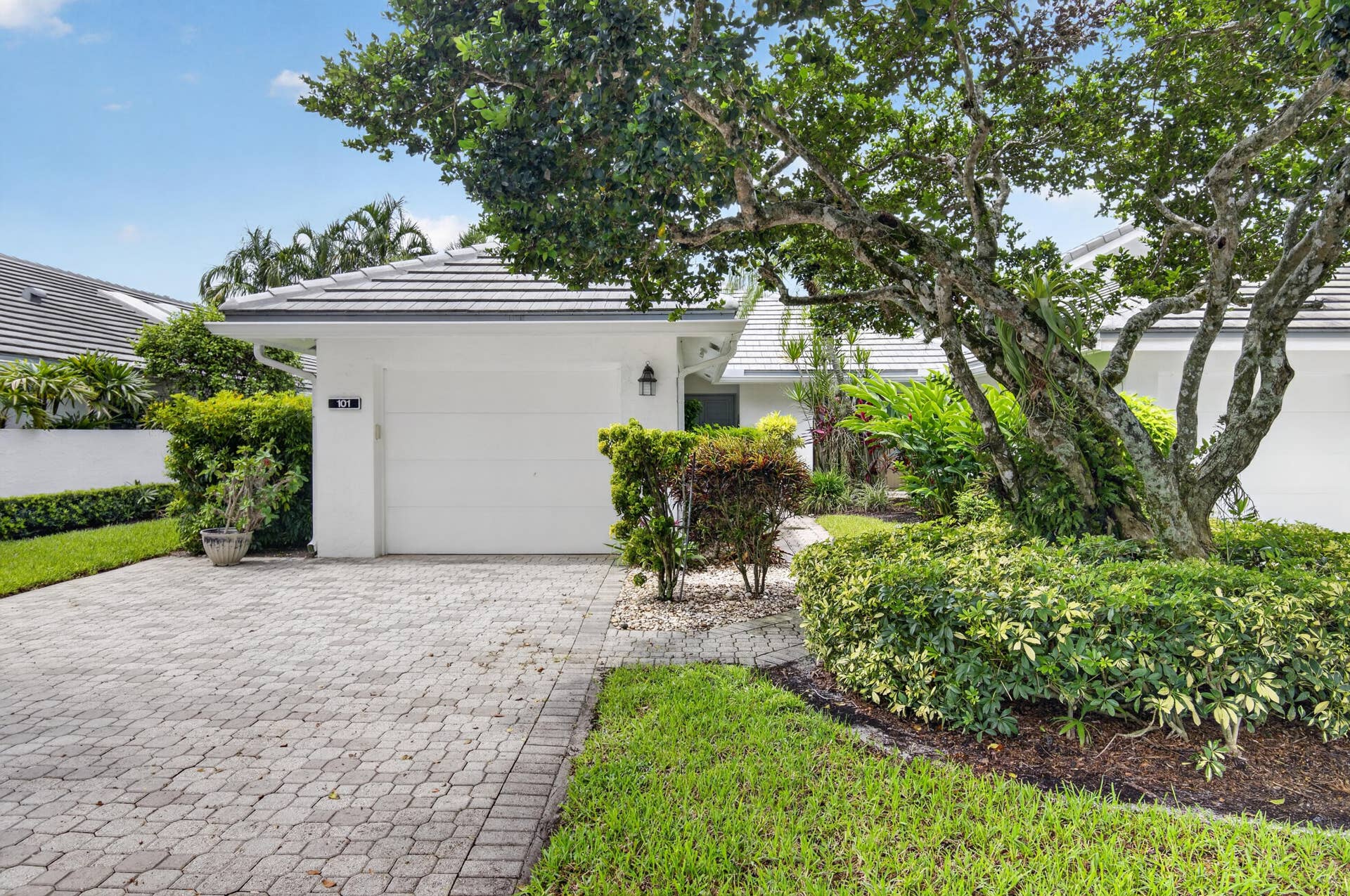 20065 Waters Edge Drive, #101, Boca Raton, FL 33434 White exterior with a tiled roof, paver driveway, and an attached garage