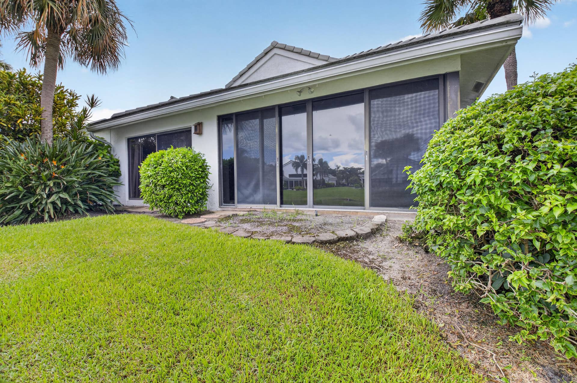 20065 Waters Edge Drive, #101, Boca Raton, FL 33434 Expansive rear lawn, mature landscaping, and multi-panel sliding glass doors