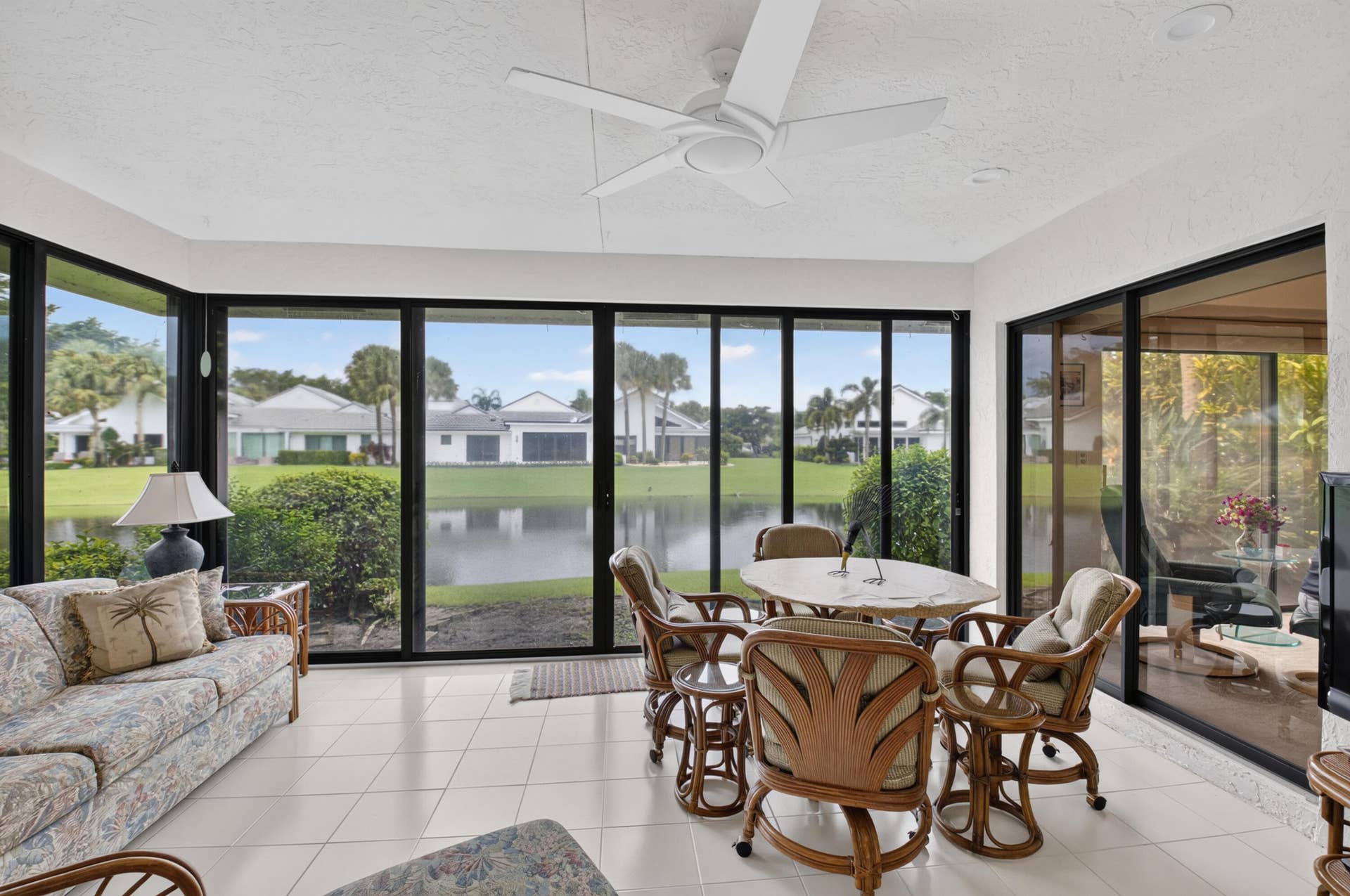 20065 Waters Edge Drive, #101, Boca Raton, FL 33434 Screened lanai featuring expansive glass panels, white tile flooring, and a ceiling fan