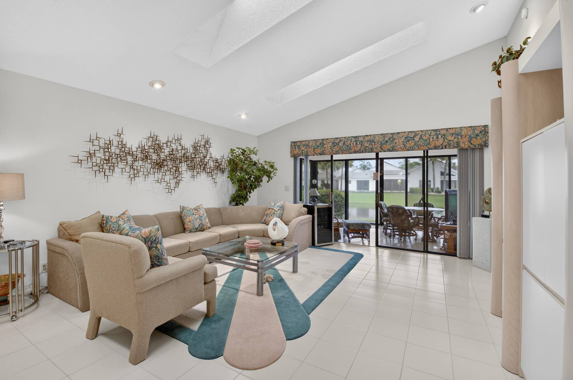 20065 Waters Edge Drive, #101, Boca Raton, FL 33434 Vaulted ceiling with recessed lighting, tile flooring, and a full wall of glass sliders overlooking small lake