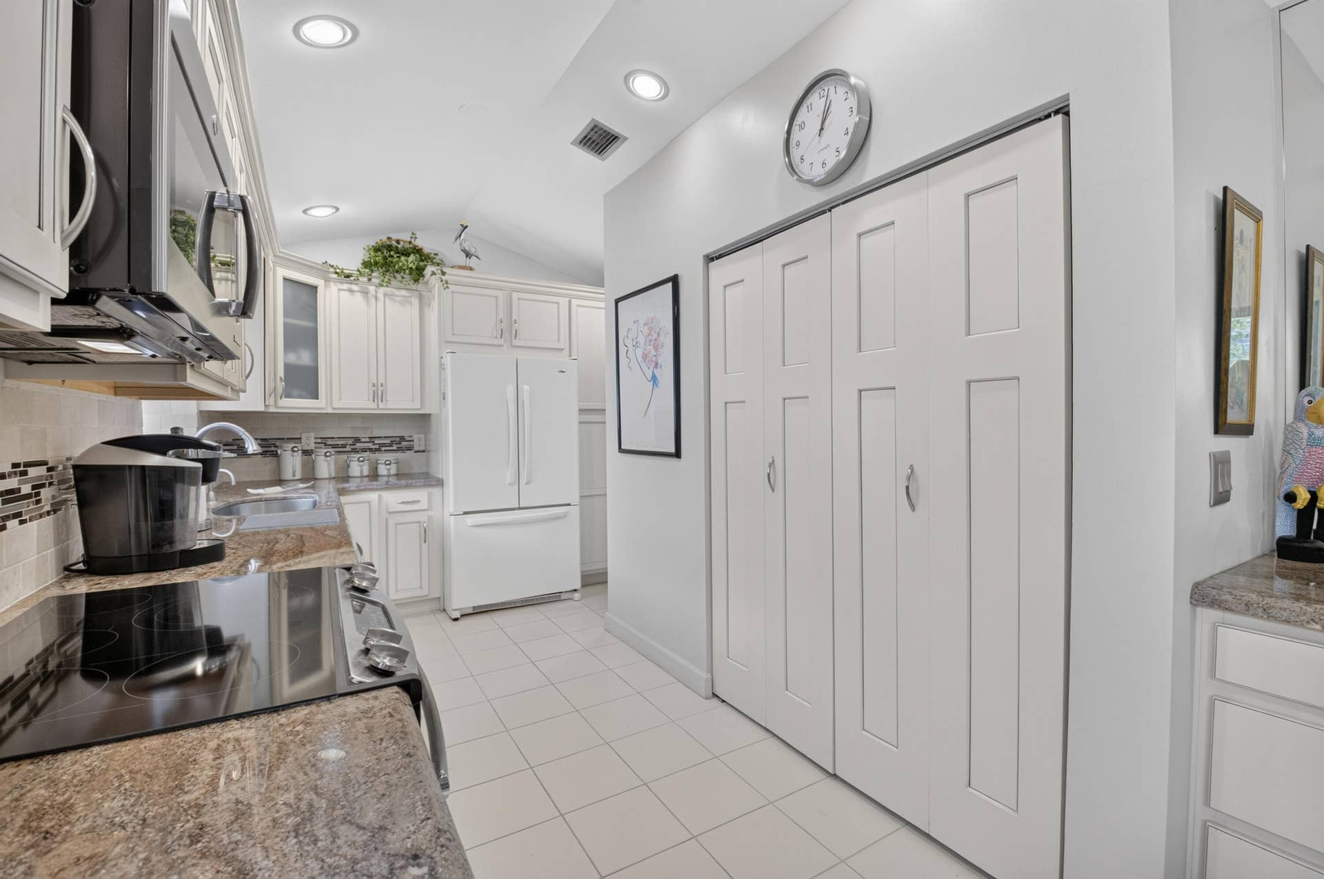 20065 Waters Edge Drive, #101, Boca Raton, FL 33434 Vaulted ceiling, recessed lighting, white cabinetry, tile flooring, and a patterned backsplash