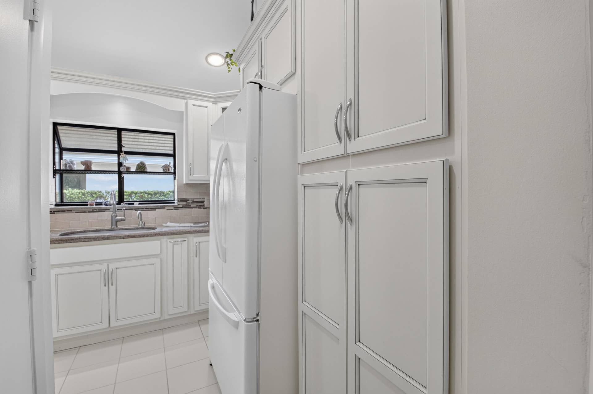20065 Waters Edge Drive, #101, Boca Raton, FL 33434 White shaker-style cabinetry, tile flooring, built-in storage, and a stainless steel sink with a single-handle faucet