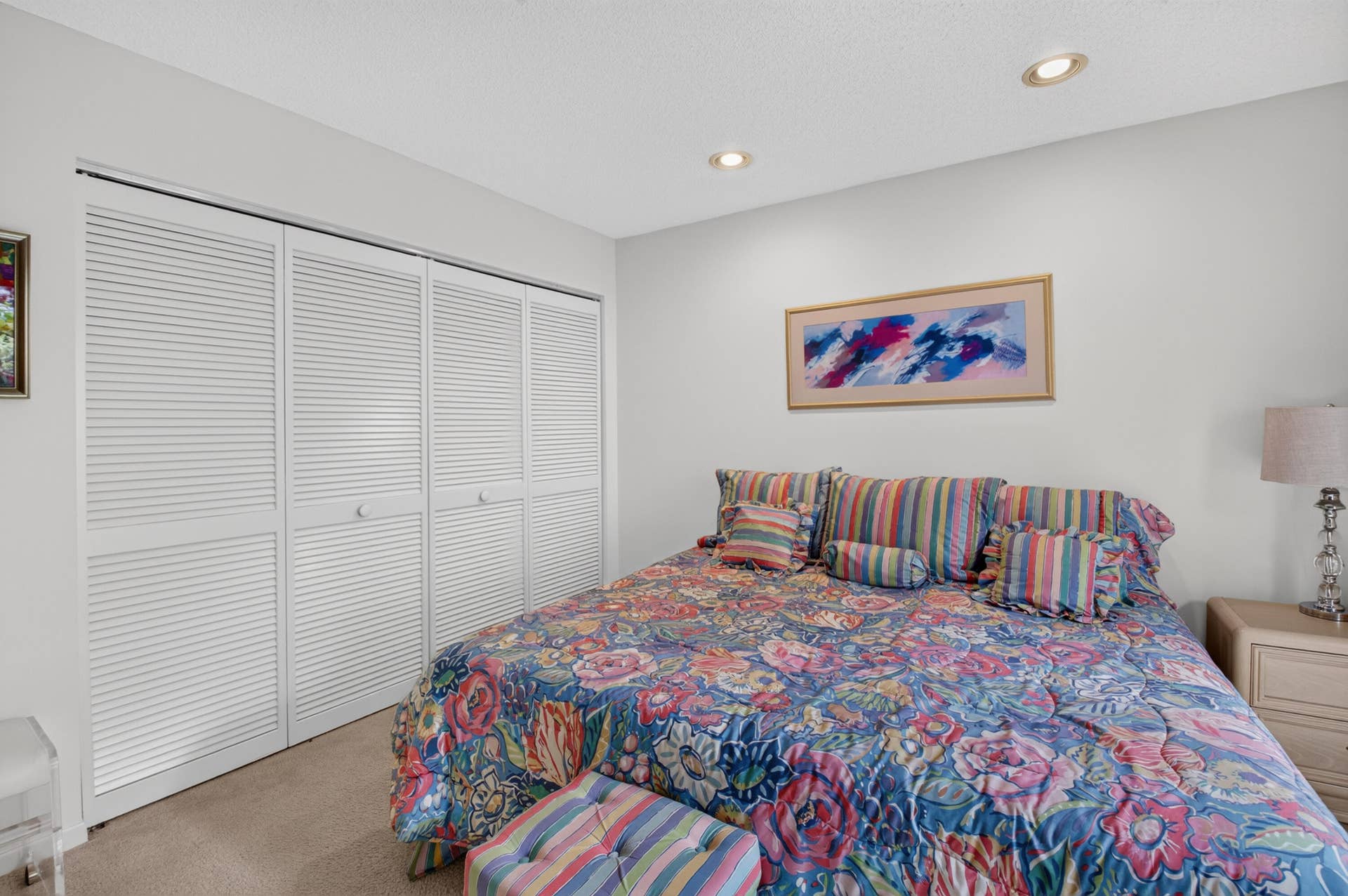 20065 Waters Edge Drive, #101, Boca Raton, FL 33434 Bright secondary bedroom featuring carpeted flooring, louvered closet doors with multiple panels, recessed ceiling lighting, and coordinating striped bedding
