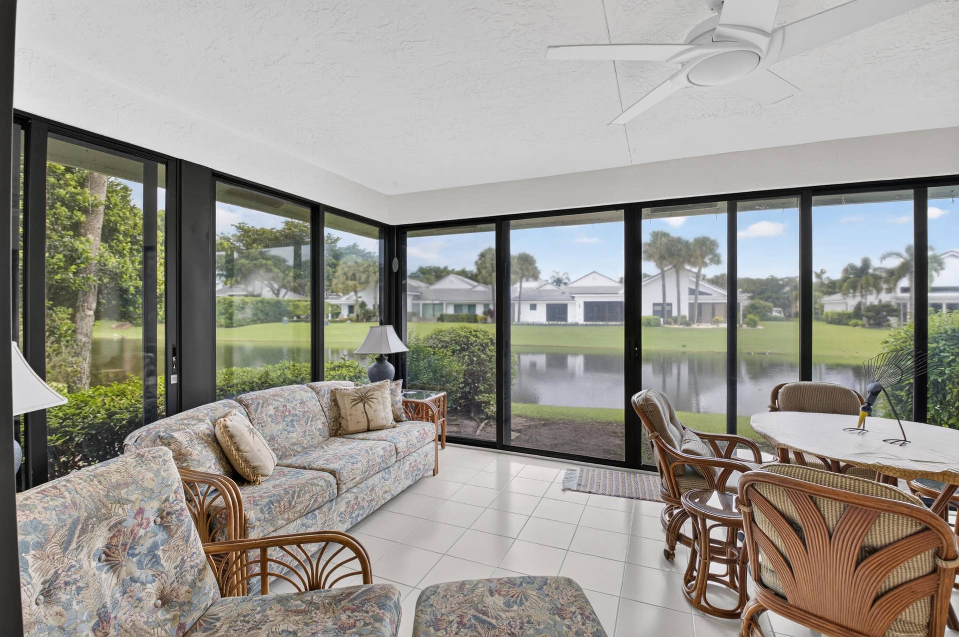 20065 Waters Edge Drive, #101, Boca Raton, FL 33434 Sunlit sunroom with expansive sliding glass doors and transom windows framing water and landscape vistas
