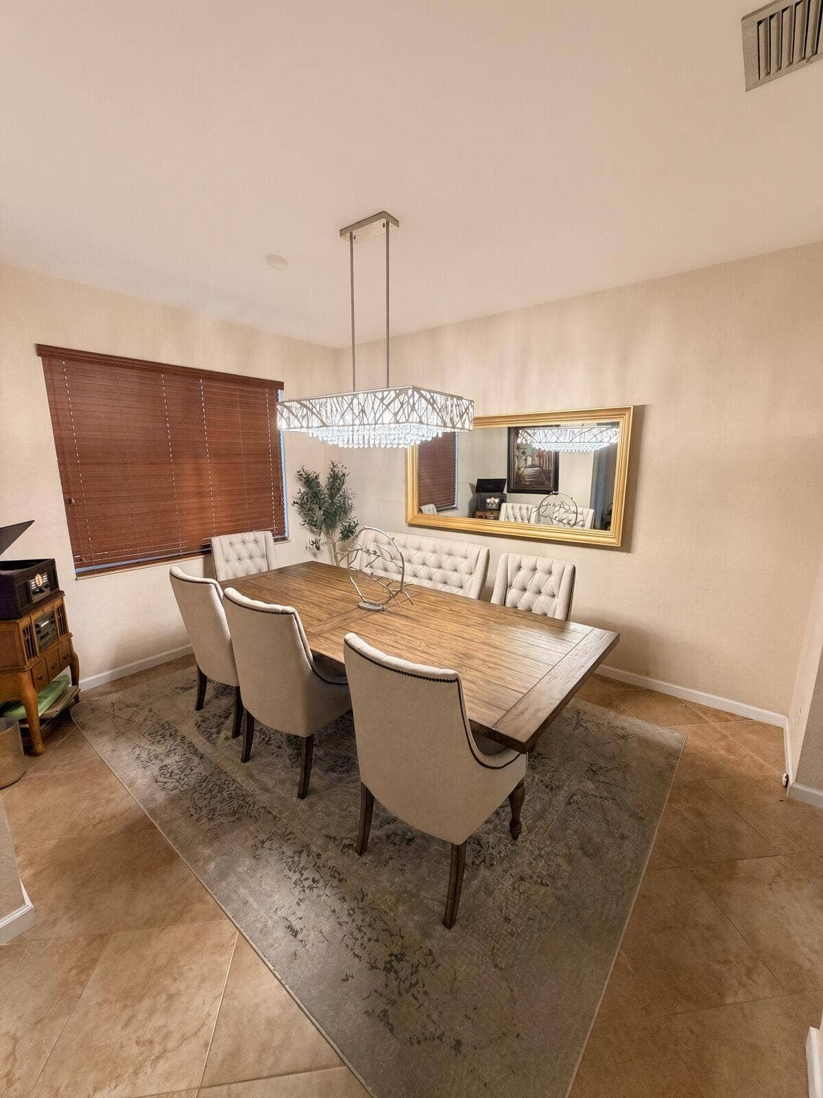 Recessed lighting and a rectangular crystal chandelier illuminate this dining area