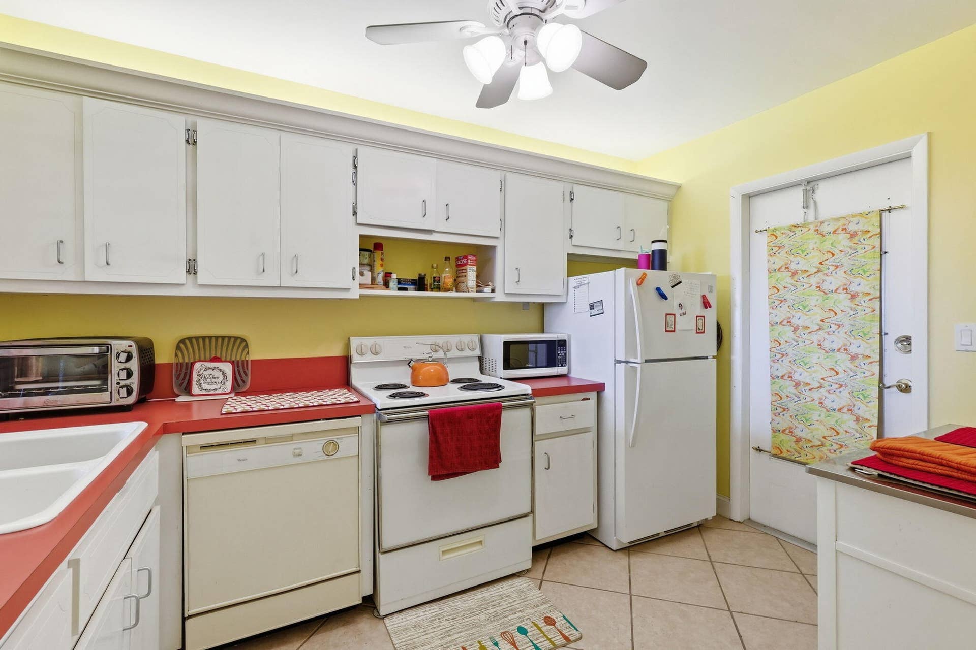 White upper and lower cabinetry, red countertops, and white appliances