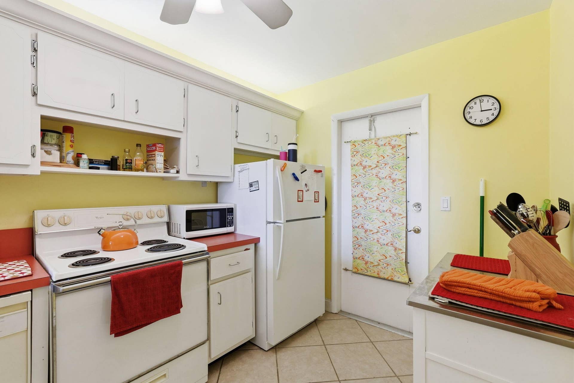 White cabinetry with chrome hardware, an electric range, and a ceiling fan with integrated lighting