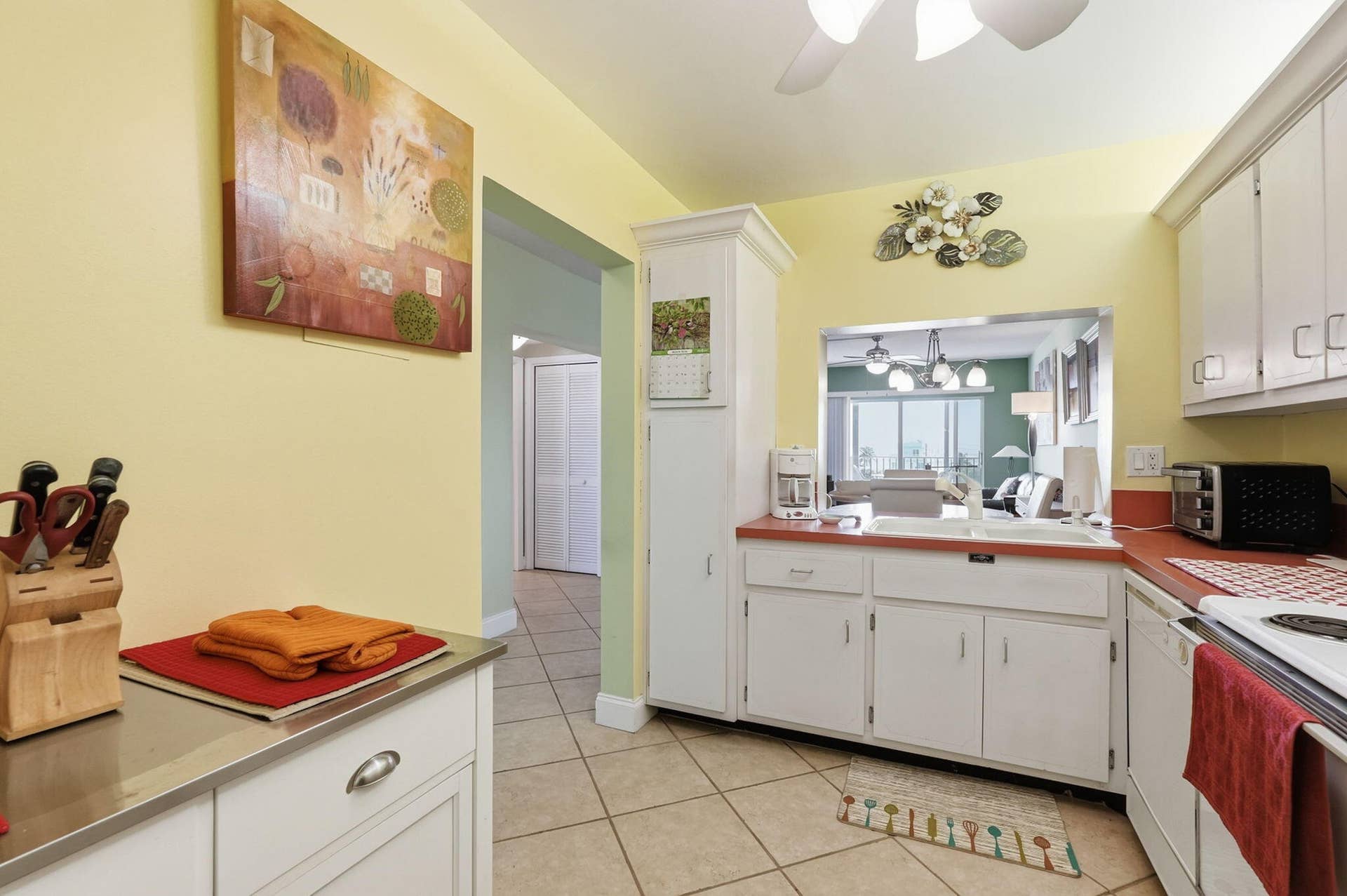 Kitchen featuring tile flooring, white cabinetry, red countertops, a pass-through opening, and a ceiling fan