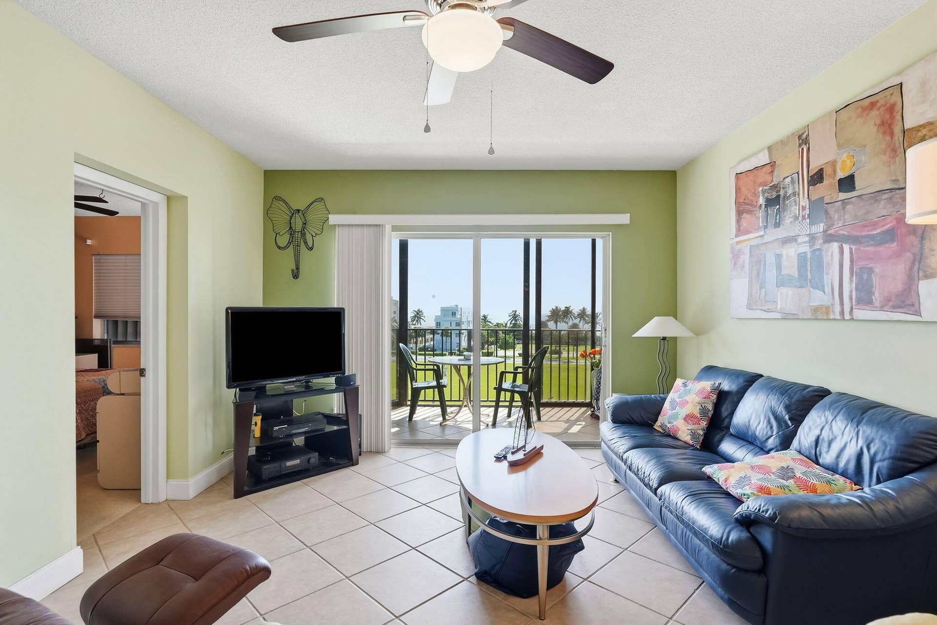 Ceiling fan with integrated lighting, tile flooring, sliding glass doors to outdoor balcony, and balcony with metal railing