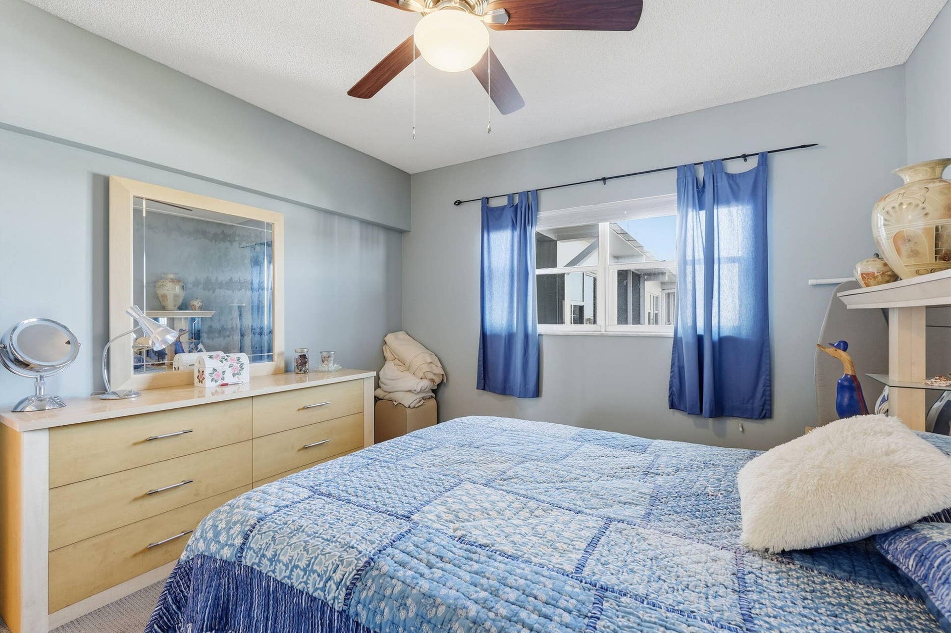 Bright room with ceiling fan, window with natural light, and spacious dresser with mirror