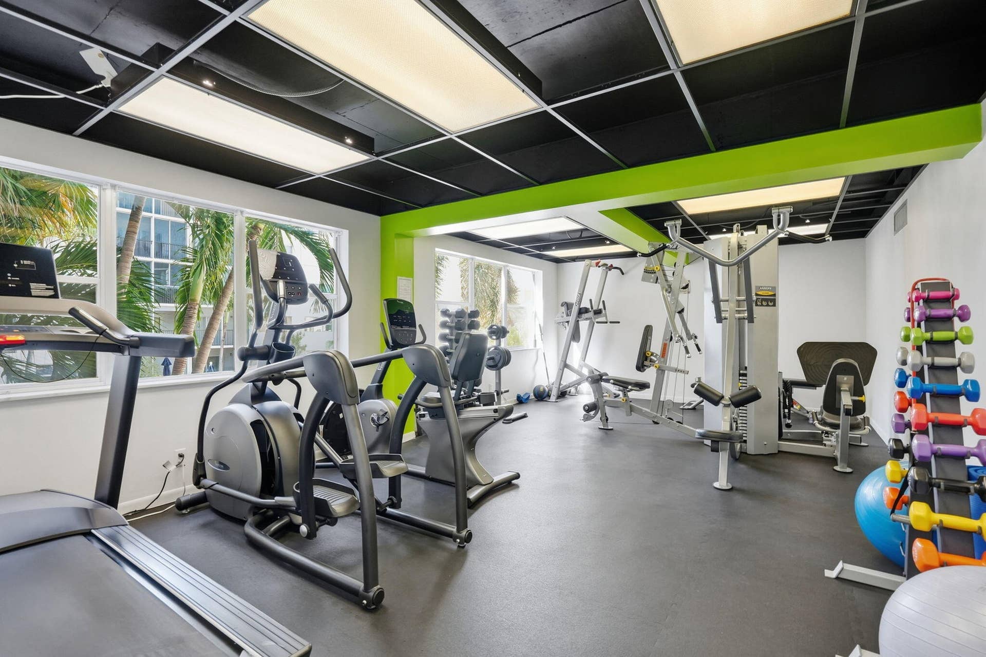 Fitness area featuring large windows, black grid ceiling with integrated lighting, and resilient flooring