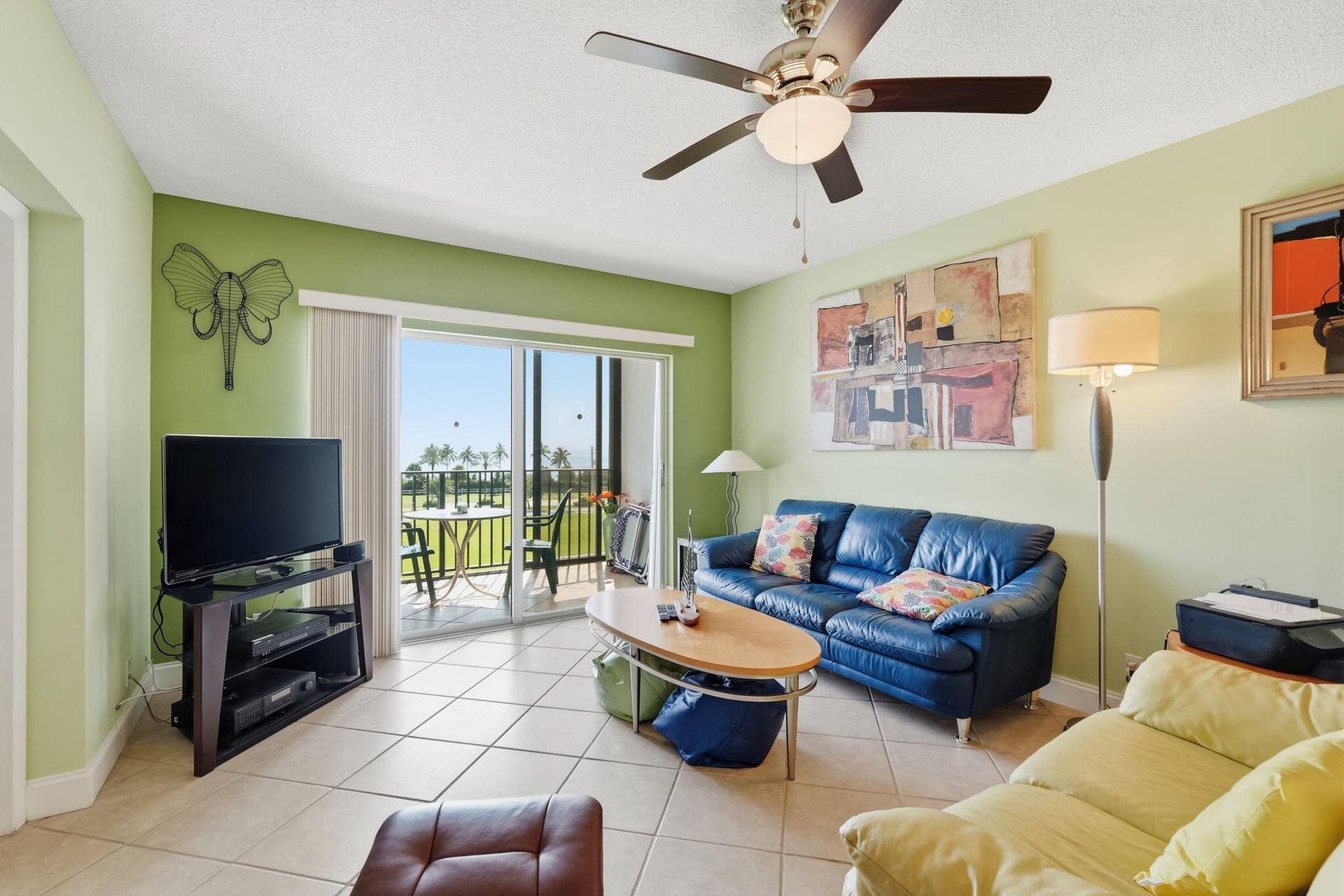Tiled flooring, ceiling fan with integrated lighting, sliding glass door, and a private balcony with a wrought iron railing