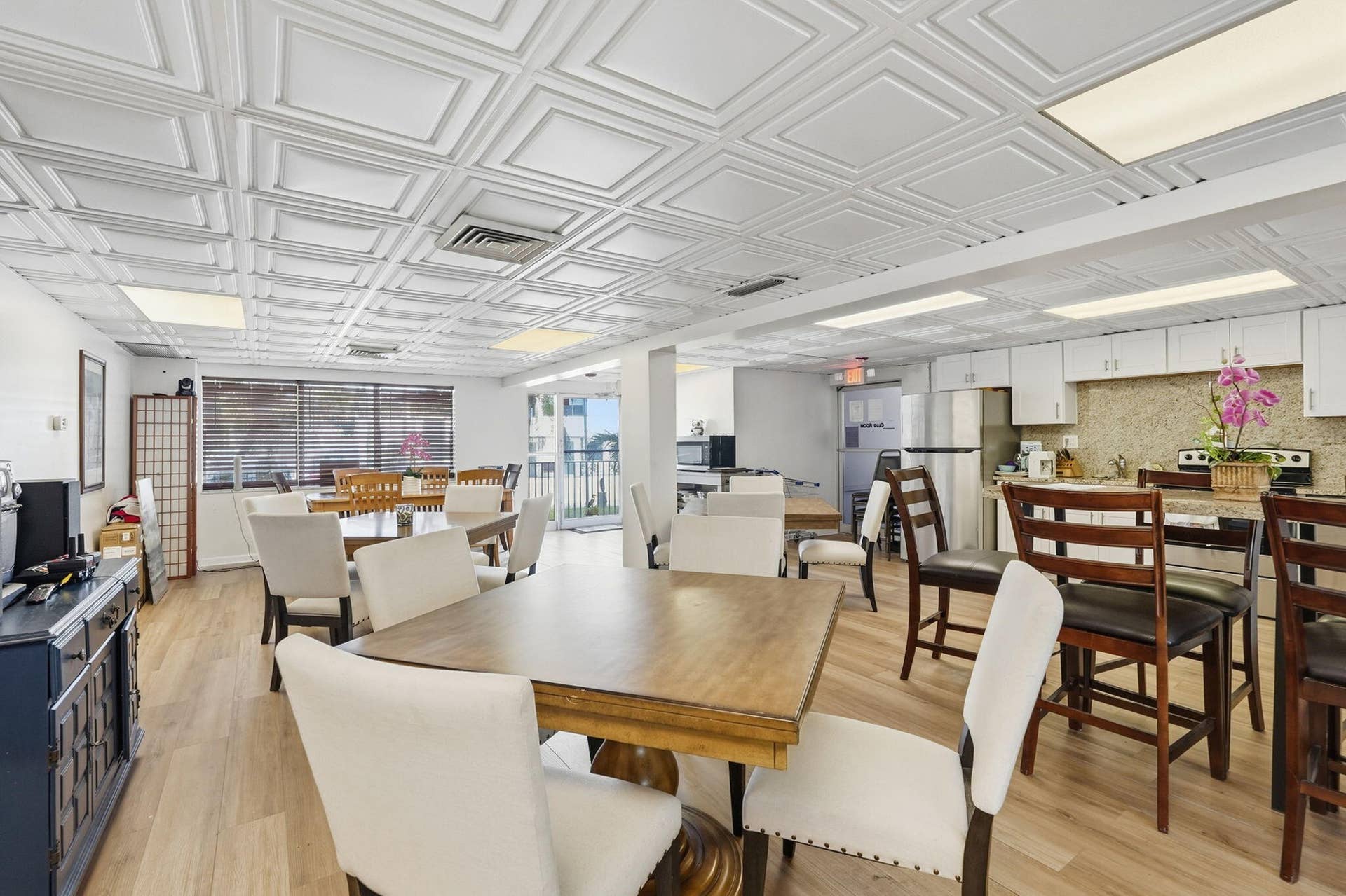 Recessed ceiling lighting, wood-finish flooring, white cabinetry, integrated stainless steel appliances, and a textured backsplash