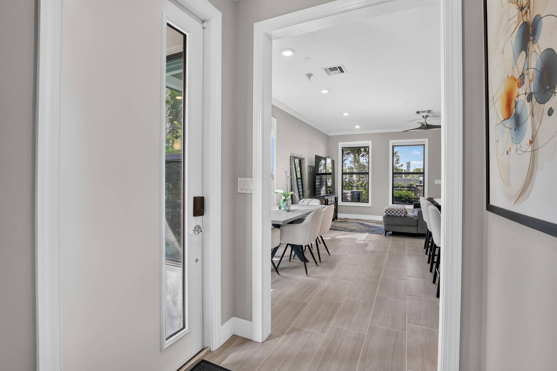 765 NW 84TH Terrace, Plantation, FL 33324 Entryway with a full-light door, leading to an open-concept living area featuring wood-finish tile flooring, recessed lighting, and multiple windows