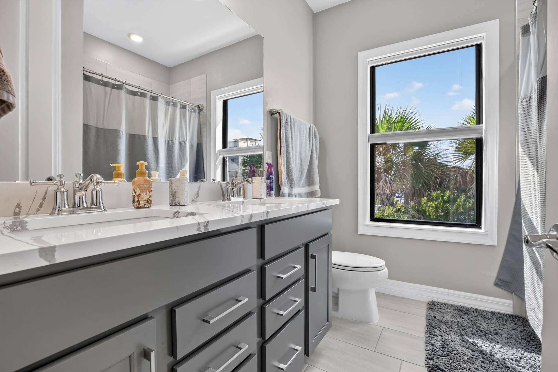 765 NW 84TH Terrace, Plantation, FL 33324 Dual vanity with a white countertop and undermount sinks, gray cabinetry with modern hardware, framed mirror, and a walk-in shower with a shower curtain
