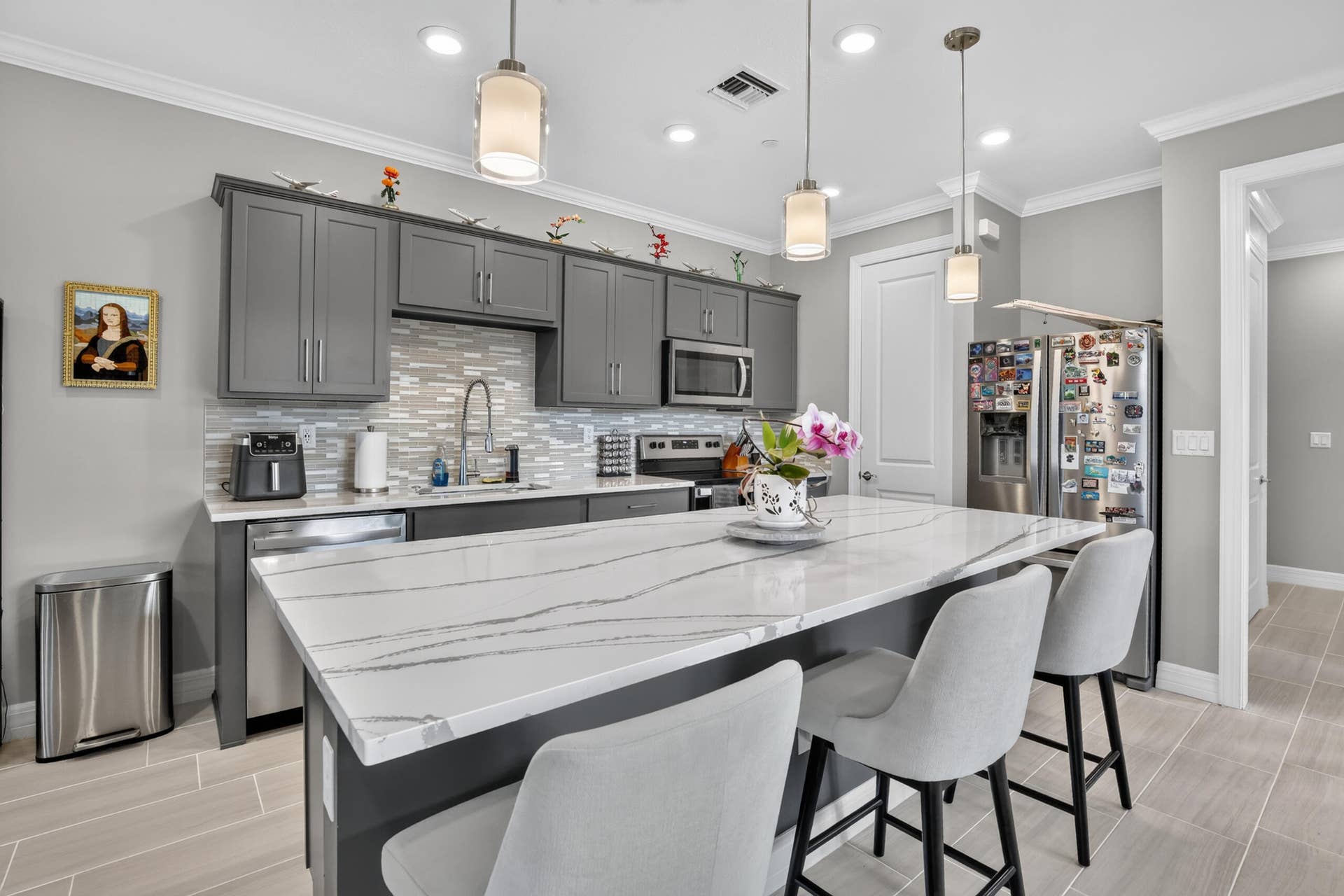 765 NW 84TH Terrace, Plantation, FL 33324 Modern kitchen featuring gray cabinetry, a mosaic tile backsplash, stainless steel appliances, and a substantial island with a white countertop